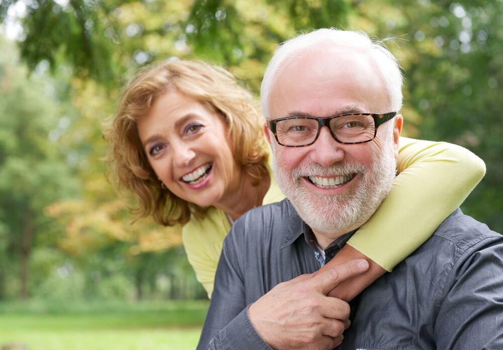 older couple smiling in front of tree